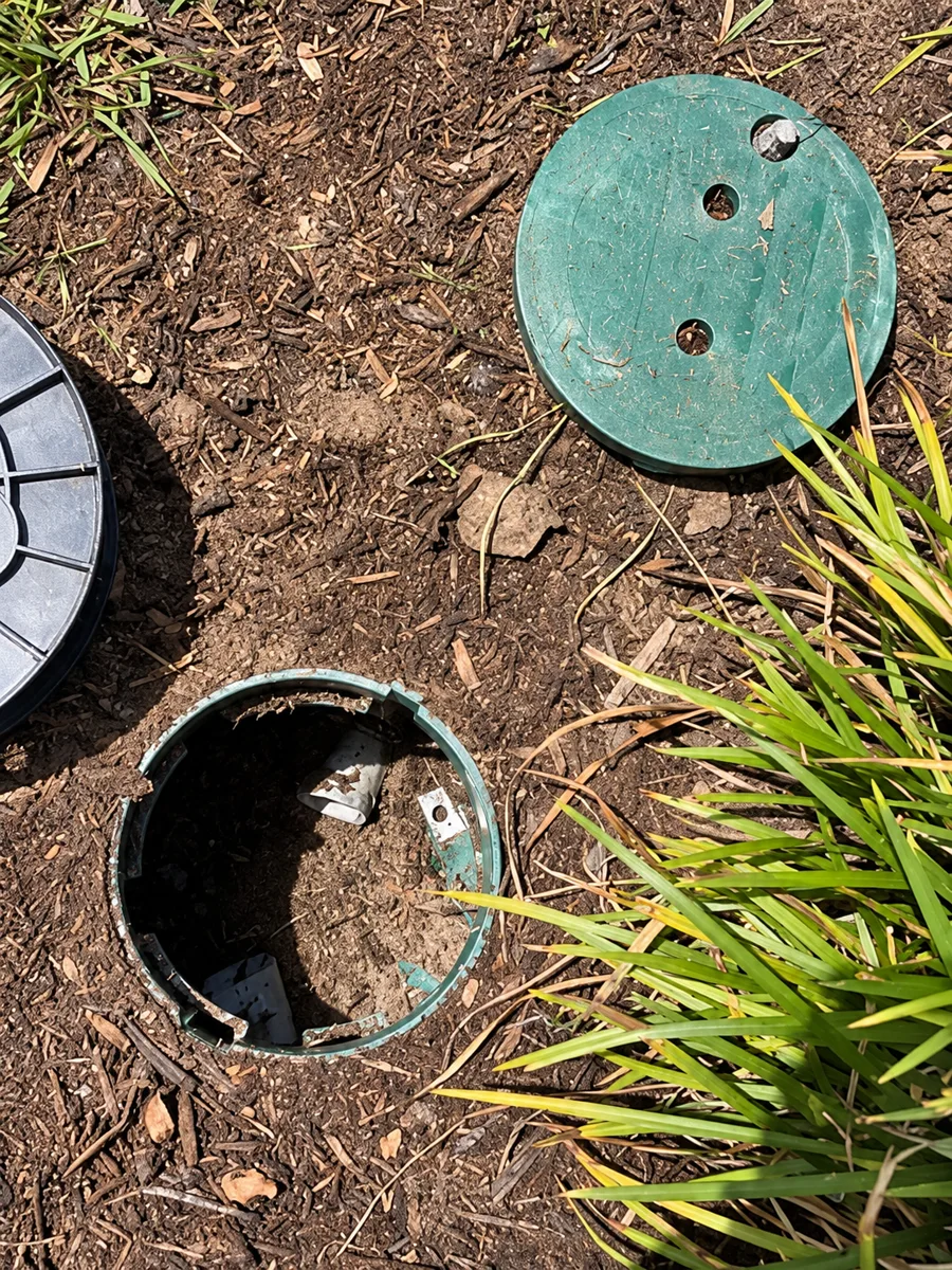 Open round underground access boxes beside planting